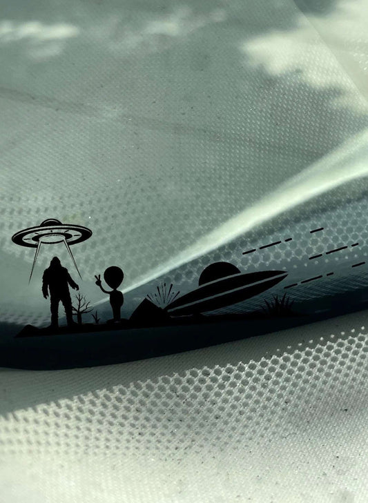 Sasquatch Abduction Decal featuring a Sasquatch standing on land with a UFO above his head, next to the Sasquatch is an alien that stepped out of a crashed UFO by Boston Print Co.