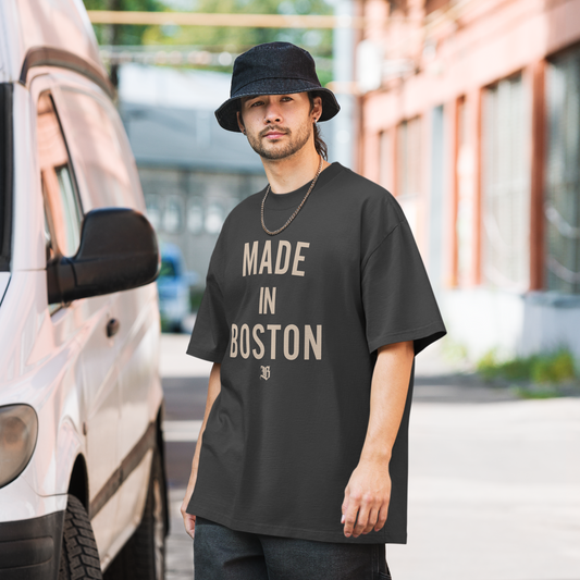 A man wearing an oversized shirt that says the words “Made In Boston” on the front in a large print with the logo of the company Boston Print Co.